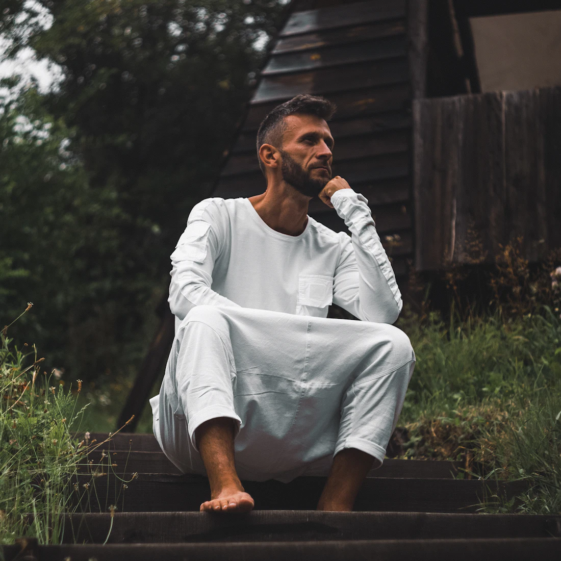 Man in a white thobe sitting on steps, deep in thought